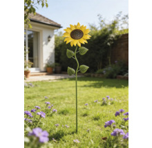 Tuinsteker zonnebloem van metaal op een gazon in een lichte tuin met bloemen.