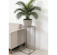 Vierkante plantenstandaard van grijs metaal met verticale spijlen, met een groene plant in pot naast een bank.