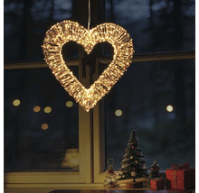 Verlicht decoratiehart van metaaldraad met talrijke warmwitte LED-lampjes, hangend voor een raam met kerstdecoratie.