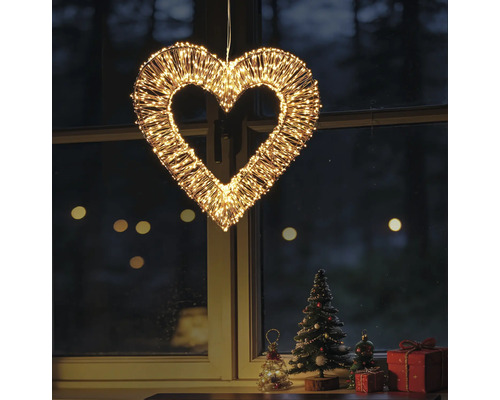 Verlicht decoratiehart van metaaldraad met talrijke warmwitte LED-lampjes, hangend voor een raam met kerstdecoratie.