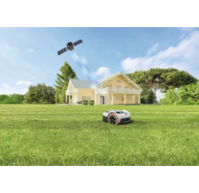 Robotmaaier op een groot gazon voor een huis met twee verdiepingen, satellietnavigatie via signalen vanuit de ruimte.