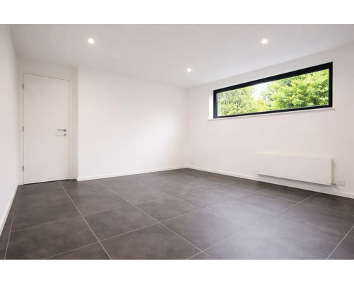 Moderne lege kamer met donkergrijze vloertegels, witte muren, een raam met zwart kozijn en een witte binnendeur.