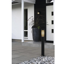 Moderne buitenverlichting met zwarte sokkelamp en bijpassende wandlamp bij de entree met plantenbak en terrastegels.