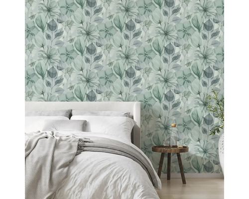Moderne, lichte slaapkamer met vliesbehang met bloemenpatroon in aquarellook, een bed en een houten bijzettafel.