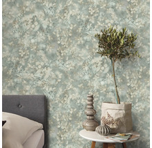 Vliesbehang met bloemenpatroon in vintagestijl in de slaapkamer achter een grijs gestoffeerd bed en een bijzettafel met olijfboom.