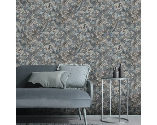 Vliesbehang met bloemmotief in een moderne woonkamer met grijze bank en een ronde bijzettafel.