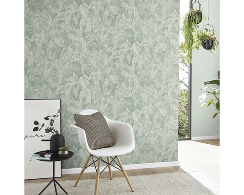 Moderne lichte kamer met vliesbehang met junglepatroon van palmbladeren, witte stoel en hangende kamerplanten.