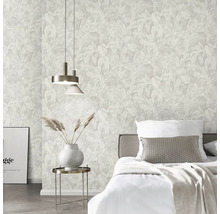 Lichte slaapkamer met vliesbehang met tropisch bladpatroon, bed met wit beddengoed en bijzettafel met vaas.