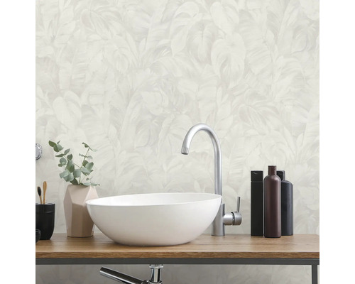 Lichte badkamer met witte opzetwastafel op houten blad, zilveren kraan en vliesbehang met palmbladmotief.