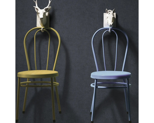 Twee bistrostoelen in geelgroen en lichtblauw hangend aan witte wandhaken in de vorm van dierenkoppen.