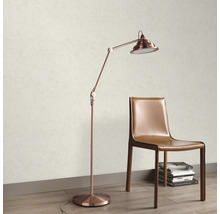 Licht gestructureerd behang in een kamer met een koperkleurige vloerlamp en een bruine lederen stoel op een vloer met houtlook.