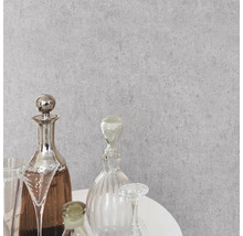 Grijs behang met betonlook en structuur in een modern interieur met glazen karaffen op een witte tafel.