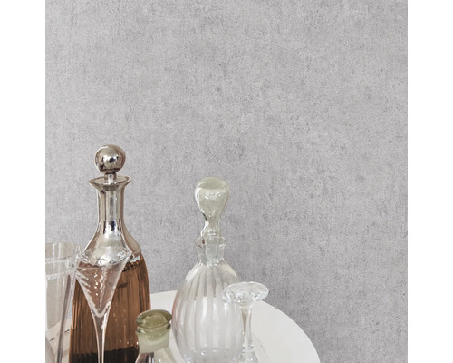 Grijs behang met betonlook en structuur in een modern interieur met glazen karaffen op een witte tafel.
