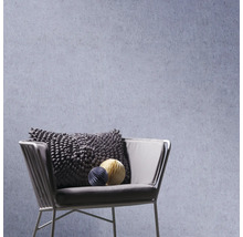 Structuurbehang achter een moderne fauteuil met een getextureerd kussen en decoratieve elementen.