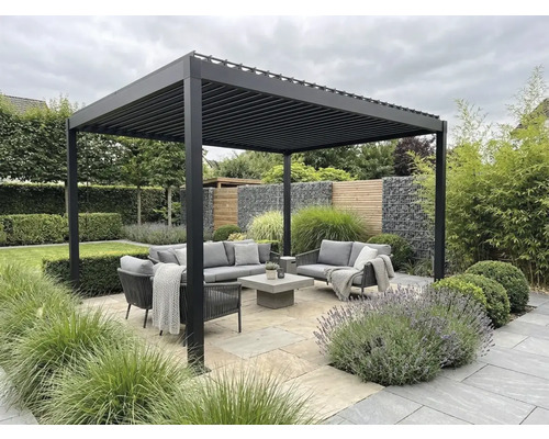 Moderne aluminium lamellenoverkapping boven een zithoek met grijze tuinmeubelen op een stenen terras, omringd door beplanting.