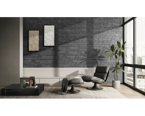 Moderne woonkamer met steenstrips in grijze baksteenlook, een fauteuil met voetenbank, een groot raam en een kamerplant.