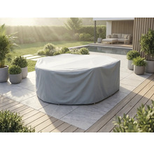 Grijze afdekhoes voor een ronde tuinmeubelset op een licht stenen terras in een tuin met zwembad en planten.