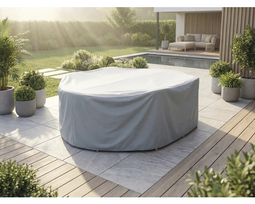 Grijze afdekhoes voor een ronde tuinmeubelset op een licht stenen terras in een tuin met zwembad en planten.