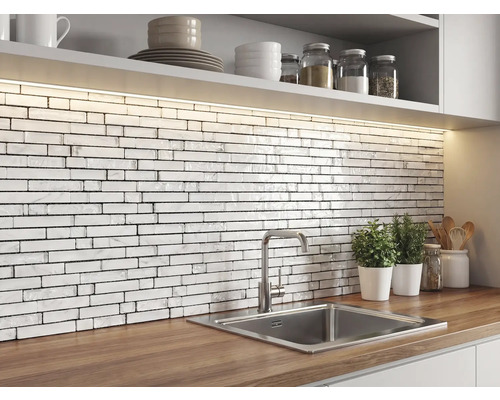Keuken met een achterwand van witte mozaïektegels in baksteenlook met marmerstructuur, houten werkblad, roestvrijstalen spoelbak en ledverlichting.