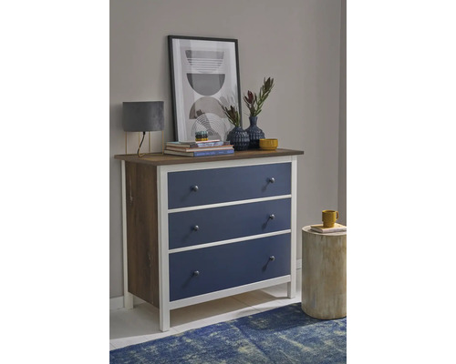Commode met drie blauwe laden, wit frame en houten bovenblad in een modern ingerichte kamer.