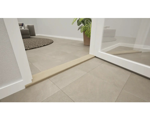 Beige overgangsprofiel bij een deurdrempel op grijze vloertegels in een lichte, modern ingerichte woonruimte.