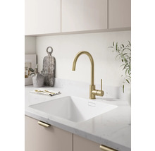 Moderne lichte keuken met een hoge keukenmengkraan, een onderbouwspoelbak en een aanrechtblad met steenlook.
