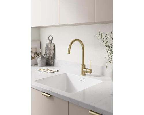 Moderne lichte keuken met een hoge keukenmengkraan, een onderbouwspoelbak en een aanrechtblad met steenlook.