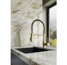 Moderne keukenkraan met spiraalveer en uittrekbare douche, eenhendelmengkraan in goudlook, gemonteerd op een licht marmeren werkblad.