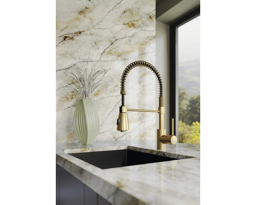 Moderne keukenkraan met spiraalveer en uittrekbare douche, eenhendelmengkraan in goudlook, gemonteerd op een licht marmeren werkblad.