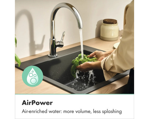 Keukenkraan met AirPower-technologie bij het wassen van kruiden in een zwarte gootsteen. Met lucht verrijkt water zorgt voor meer volume.