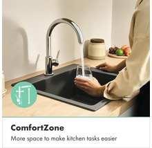 Keukenkraan in chroom met hoge uitloop, water stroomt in een glas in een donkere gootsteen, toont meer bewegingsvrijheid door ComfortZone.