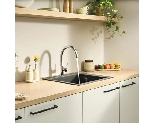Moderne, lichte keuken met een houten werkblad, een verchroomde mengkraan en een donkere inbouwspoelbak van composiet.