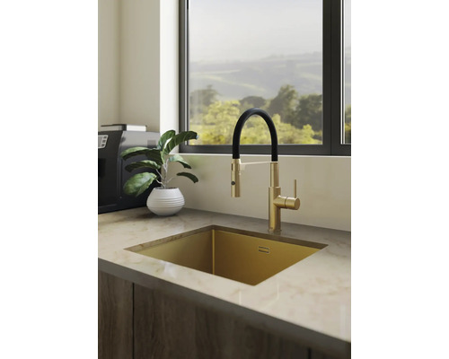 Lichte moderne keuken met gouden onderbouwspoelbak en mengkraan met zwarte slang op een aanrechtblad met marmerlook.