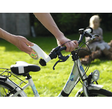Handen plakken wit plakband met tesa Logo op het stuur van een zilveren kinderfiets in een lichte tuin.