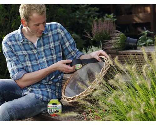 Man repareert een rieten mand met zwarte tesa Extra Power Eco Repair tape in een tuin.