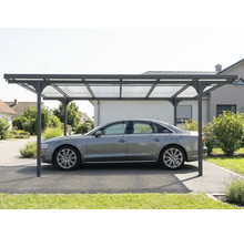 Vrijstaande moderne carport met een metalen frame en lichtdoorlatende dakpanelen, die een auto op een oprit beschermt.