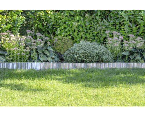 Metalen gazonrand scheidt het gazon van een border met vaste planten en struiken voor een heg.