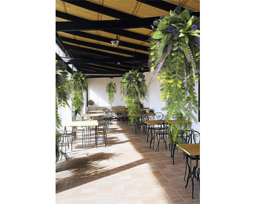 Hangende kunstplanten boven een licht terras met houten tafels en metalen stoelen.