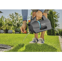 Persoon leegt een Gardena besproeiingspomp 5500 Silent op een gazon in de tuin.
