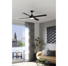 Moderne zwarte plafondventilator met vijf bladen en geïntegreerde lamp in een lichte woonkamer met bank en kamerplant.