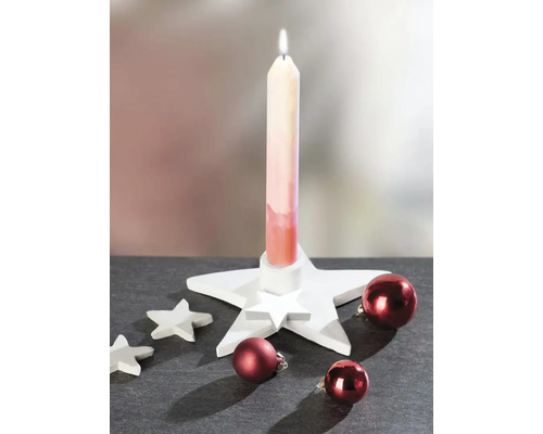 Kerstdecoratie met een witte stervormige kandelaar, een brandende kaars, kleine decoratieve sterren en rode kerstballen.