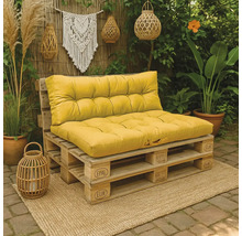 Palletbank met gele kussens gemaakt van Europallets in een gezellige tuin met boho-decoratie, planten en rieten windlichten.