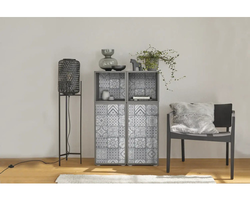 Moderne woonkamer met grijze kast met tegelpatroon, hoge zwarte lantaarn en donkere stoel met pluizig kussen.