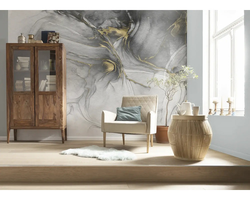 Modern ingerichte kamer met abstract fotobehang in marmerlook, houten vitrinekast, fauteuil en bijzettafel op lichte vloer.