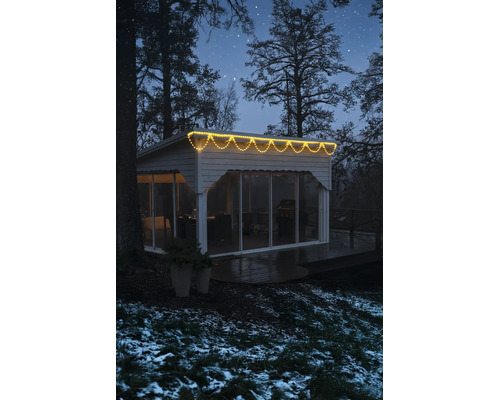 LED-ijspegelverlichting warmwit aan een modern tuinhuis in een winterse omgeving 's nachts.