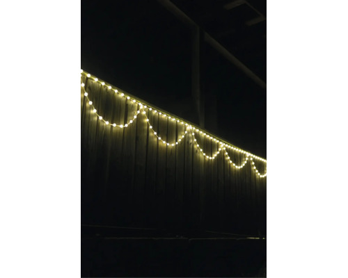LED-lichtsnoer warmwit aan een houten schutting buiten in de nacht.