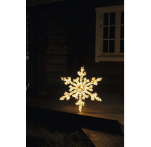 Verlichte LED-sneeuwvlok met warm wit licht als kerstdecoratie op een houten terras voor een huis bij nacht.