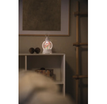 Kerst waterlantaarn met LED-verlichting en glitters op een witte plank in een kerstomgeving.