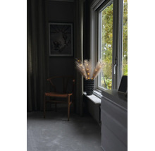 Verlichte pampasgras takken in een vaas op de vensterbank naast een houten stoel in een sfeervolle kamer.