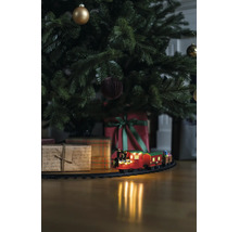 Kersttrein op rails onder een versierde kerstboom met cadeaus op een houten vloer.